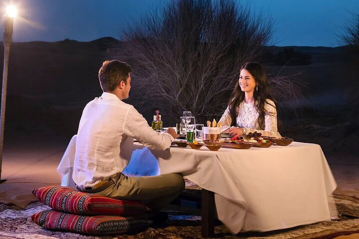 Experience romance under a starlit sky with a private dinner in the desert enjoying delicious cuisine and intimate moments surrounded by serene dunes and the quiet beauty of nature.